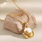 pearlescent botanical plaque pendant displayed on a stone surface