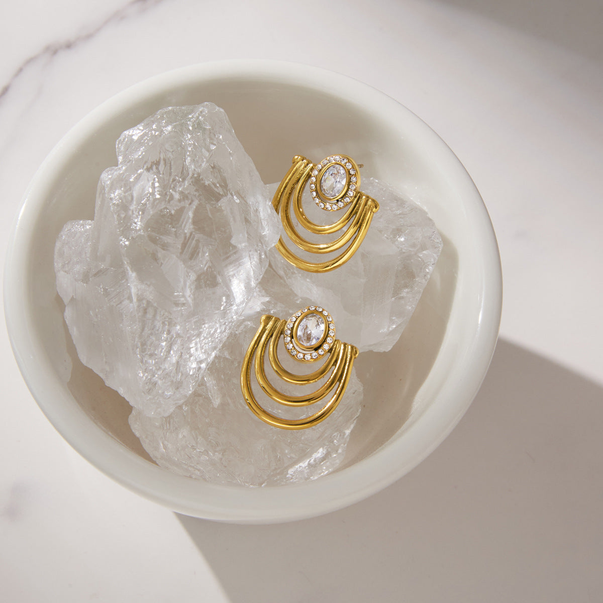 Pair of arc earrings displayed on clear stones