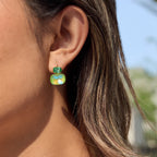 Green two-stone leverback earring worn on ear
