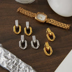 Three oval link earring finishes displayed beside a watch
