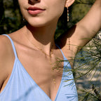 Gold tone charm Y-necklace worn with blue top