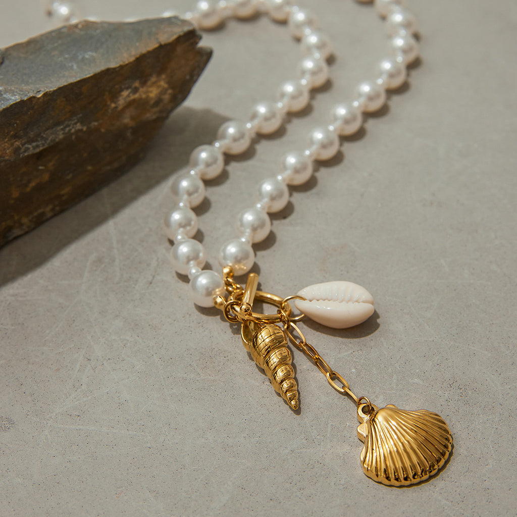 White pearl-look beads and elongated shell charm on stone