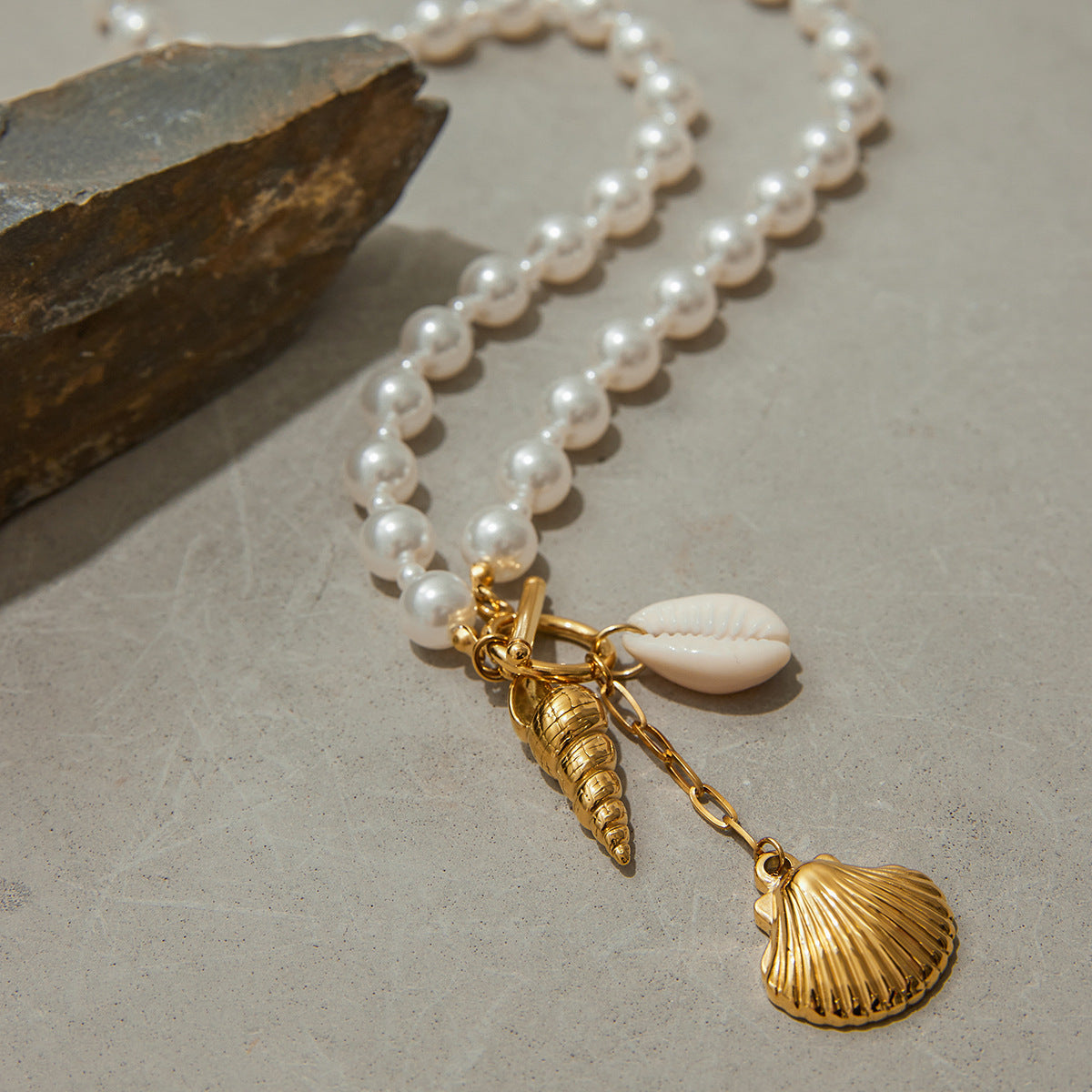 White pearl-look beads and elongated shell charm on stone