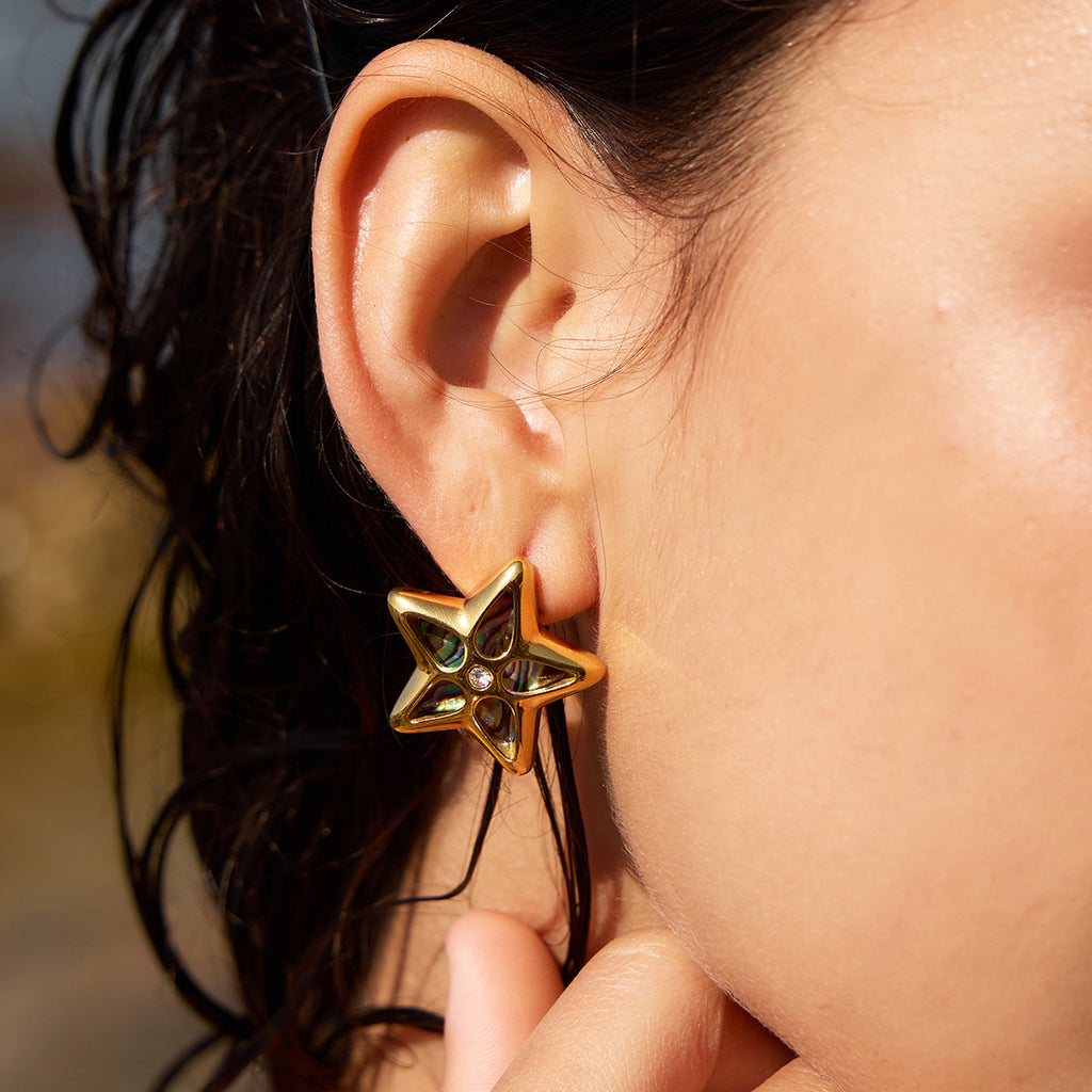 Star-shaped abalone stud shown on ear