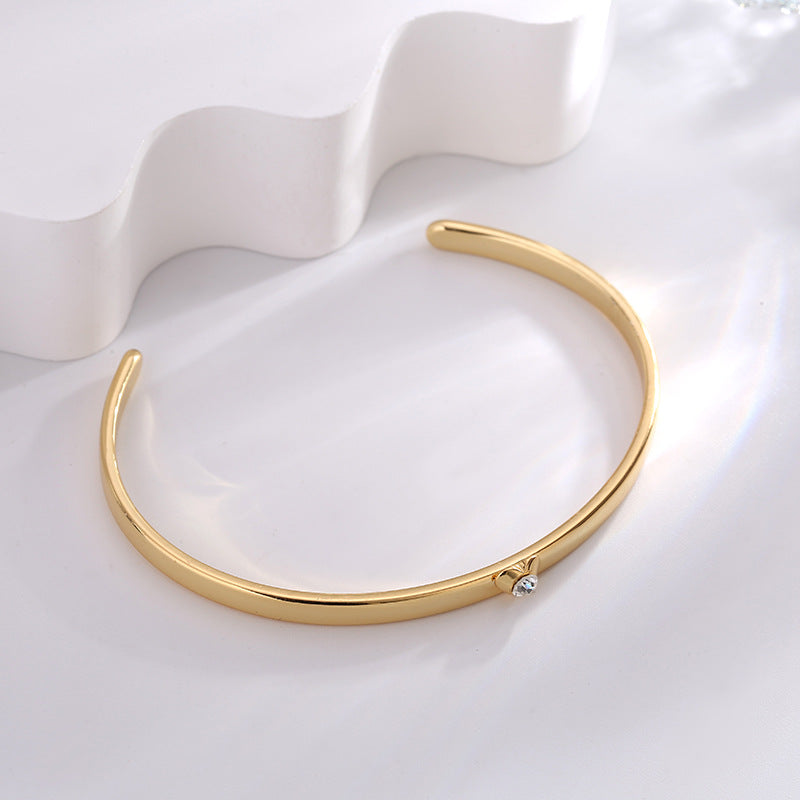 slim gold plated heart-set cuff bracelet in an angled view