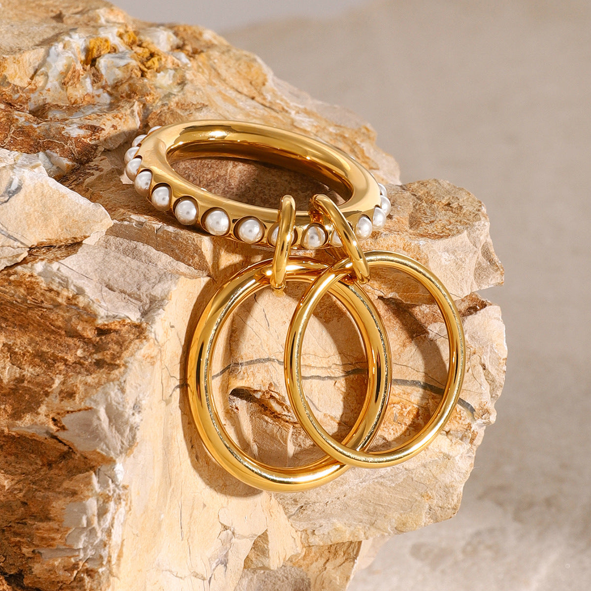 Linked triple-ring design draped over textured stone