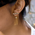 Geometric three-accent stud with long chain drapes worn on an ear
