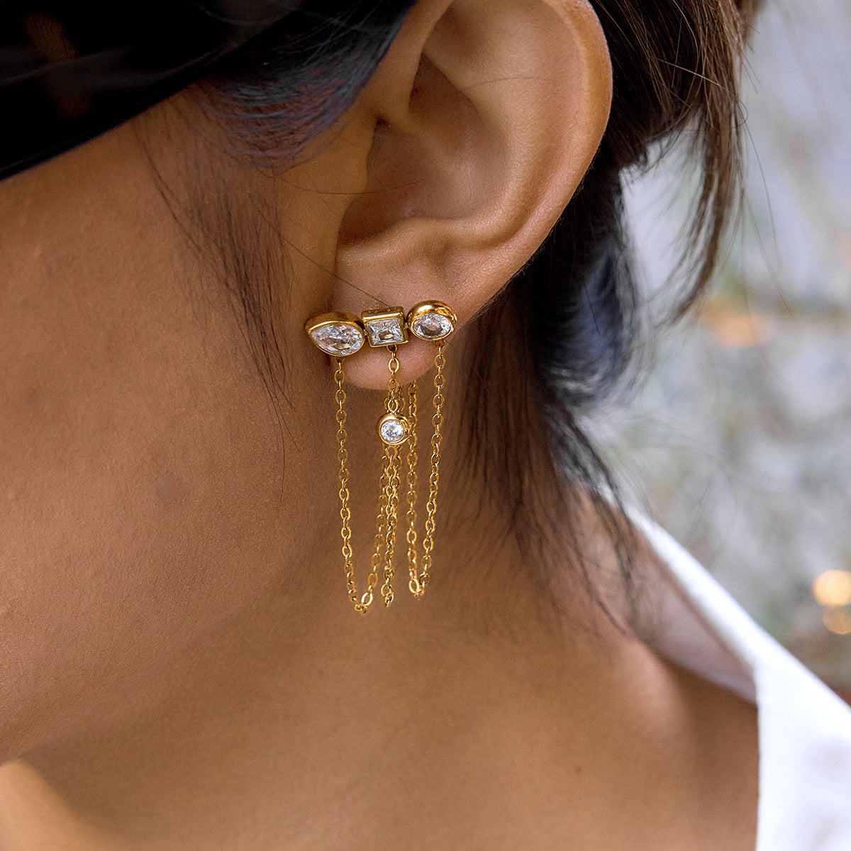 Geometric three-accent stud with long chain drapes worn on an ear