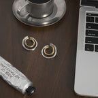 Pair of two-tone double hoop earrings on a dark desk