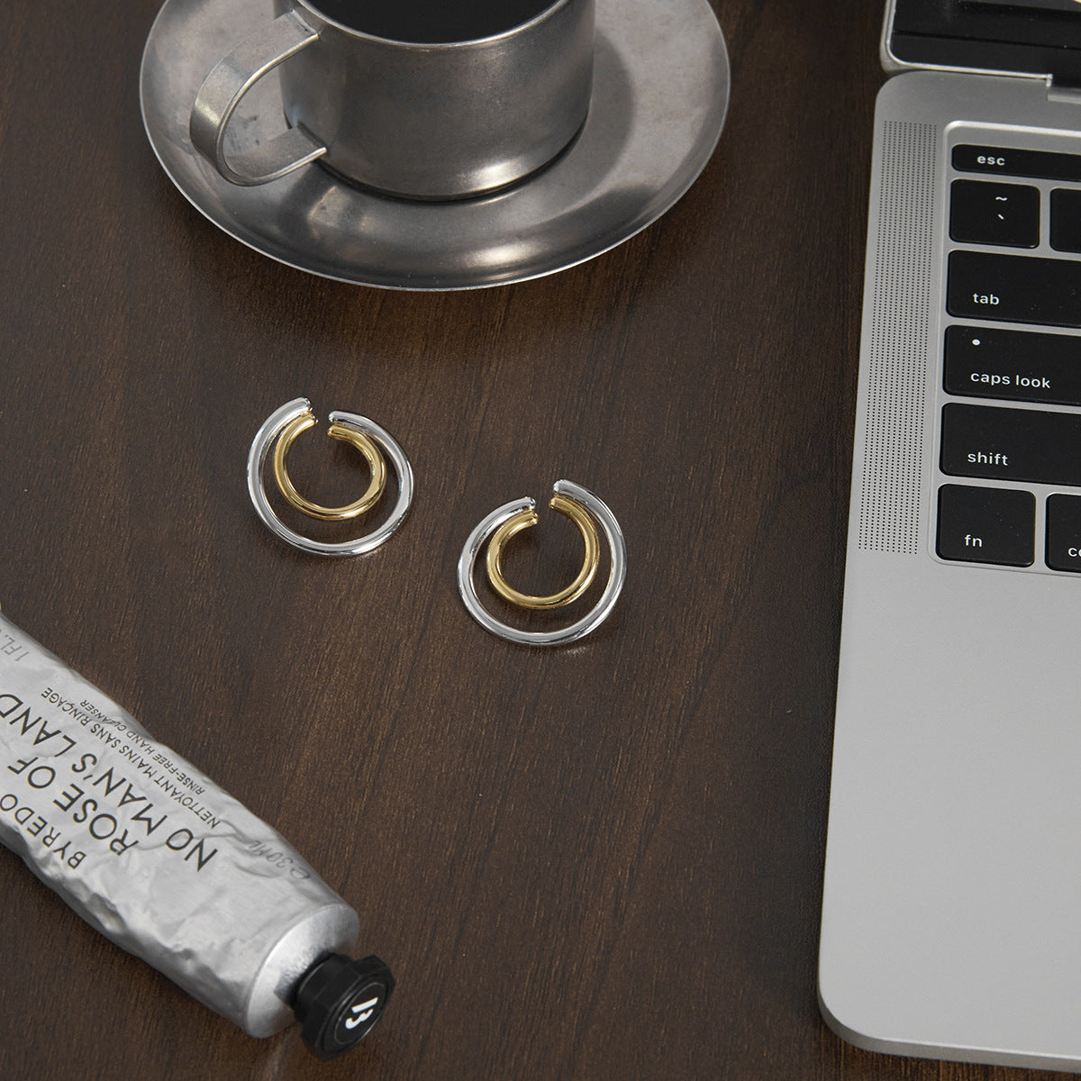 Pair of two-tone double hoop earrings on a dark desk
