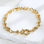 gold plated bow-knot chain bracelet arranged on a pale stone surface
