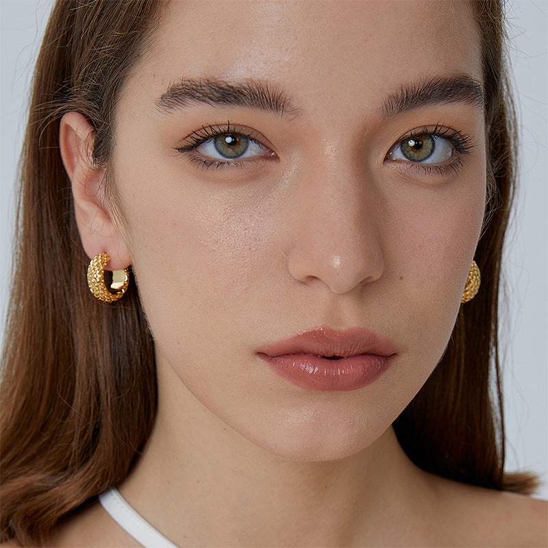wide woven gold plated hoop earrings worn on the ear