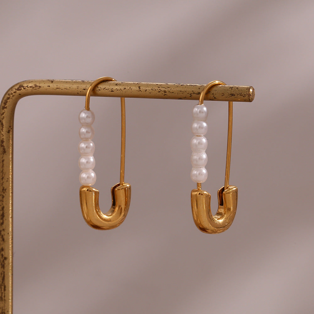 Pair of pearl pin earrings hanging from a display bar
