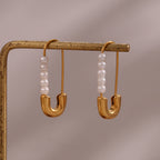 Pair of pearl pin earrings hanging from a display bar