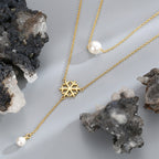 snowflake shell pearl necklace arranged between dark mineral stones