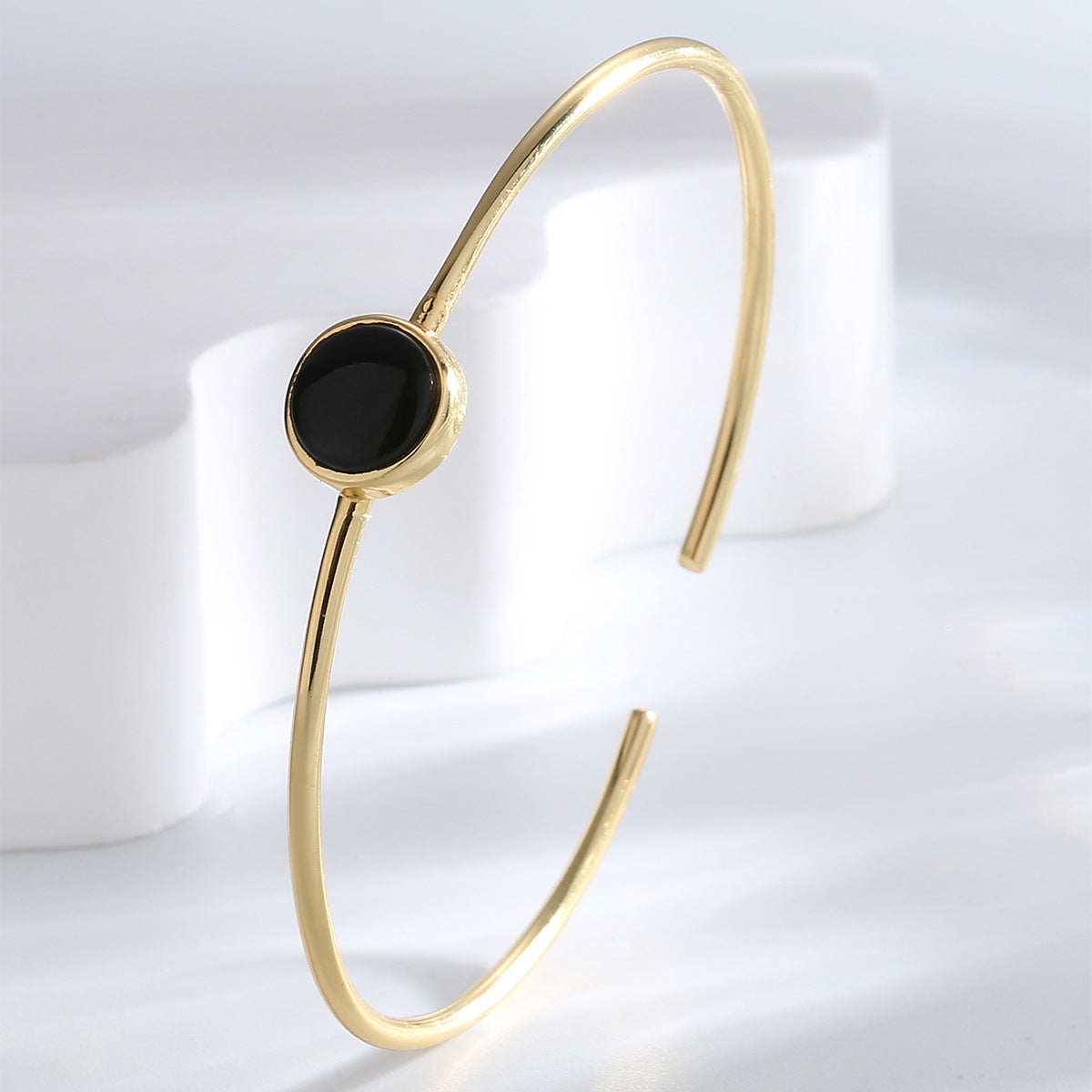 upright view of slim gold plated black agate open bangle