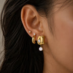 Sculpted gold-tone drop earring worn on an ear