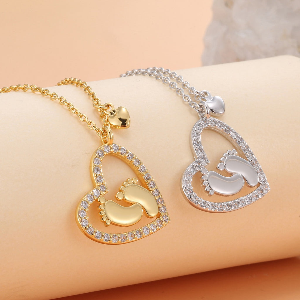 gold and silver baby footprint heart pendants with clear stone outlines