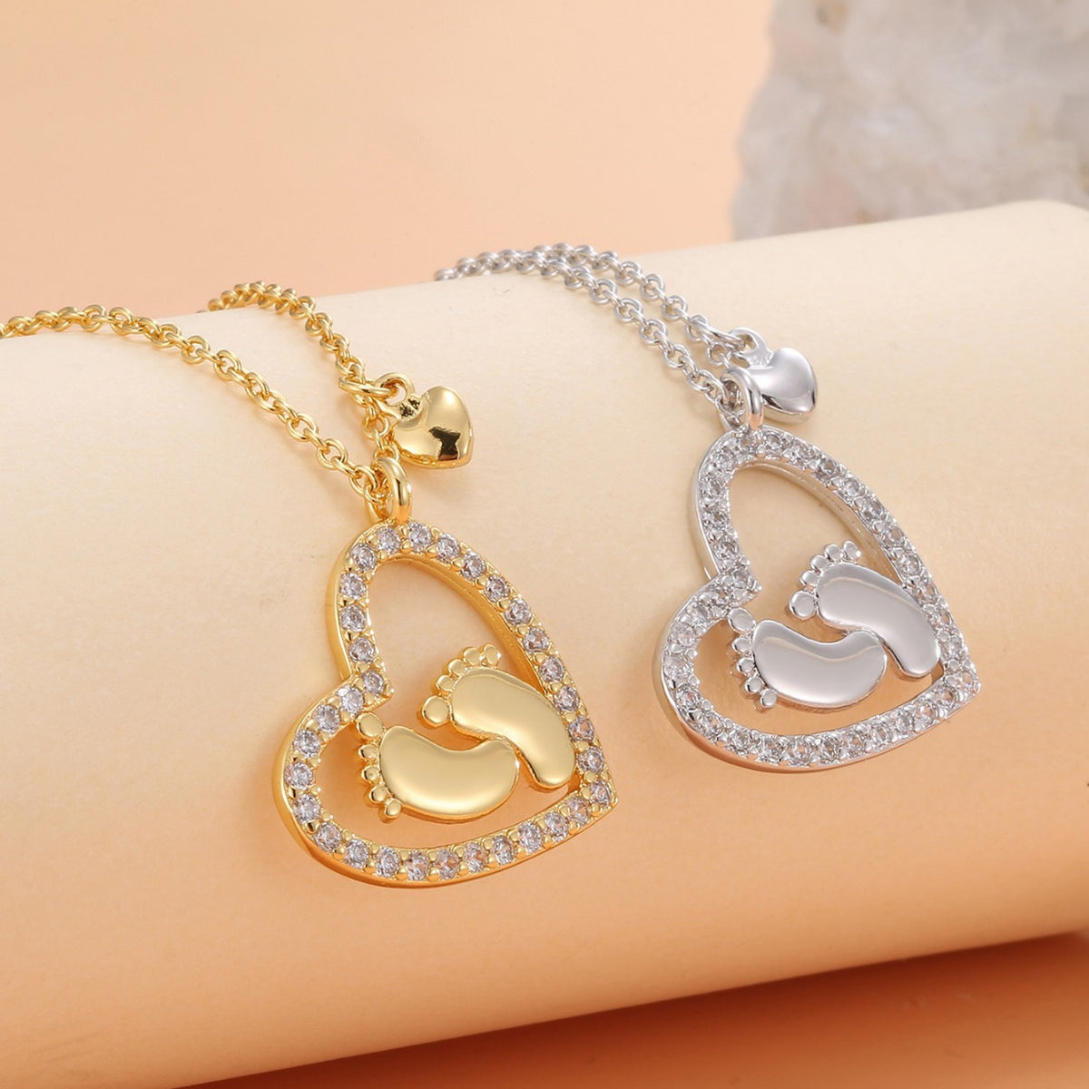 gold and silver baby footprint heart pendants with clear stone outlines