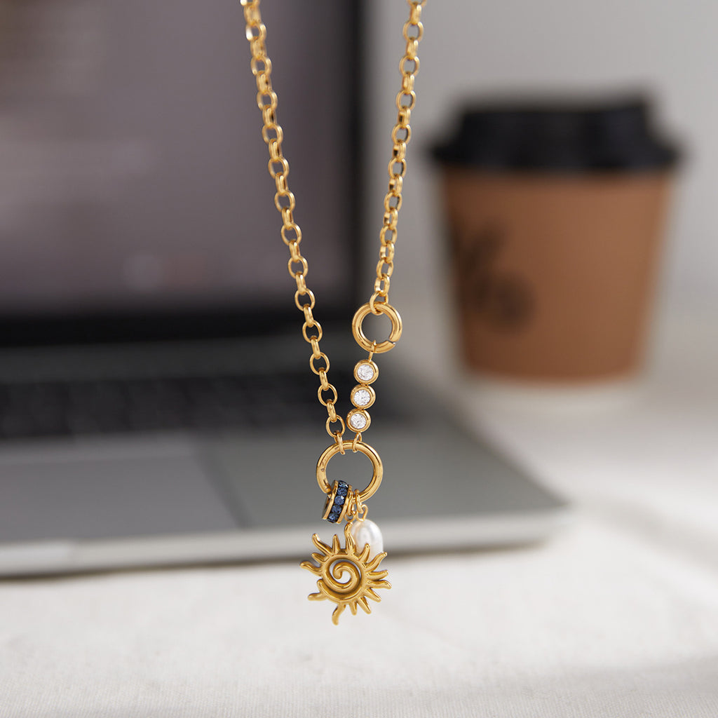 spiral sun pearl charm necklace beside a laptop