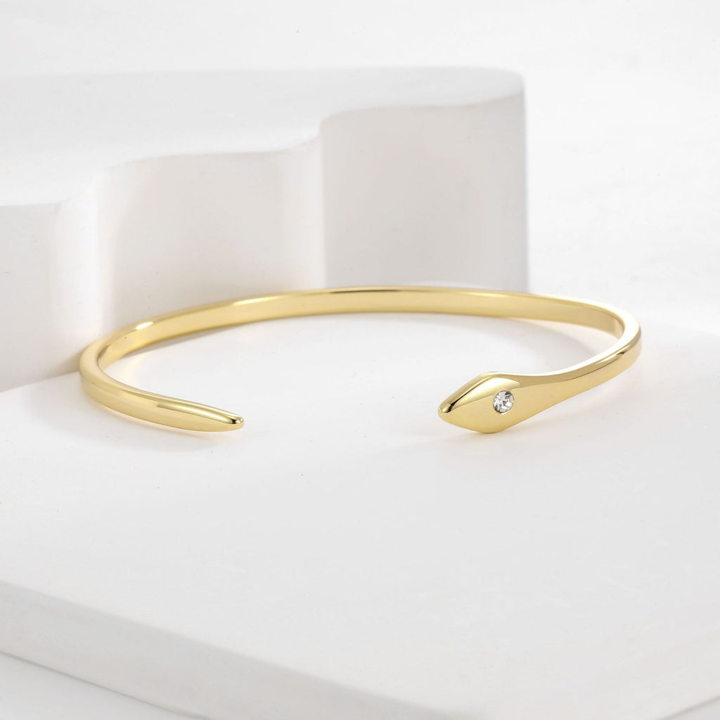 angled view of asymmetric gold plated cuff with pointed terminal