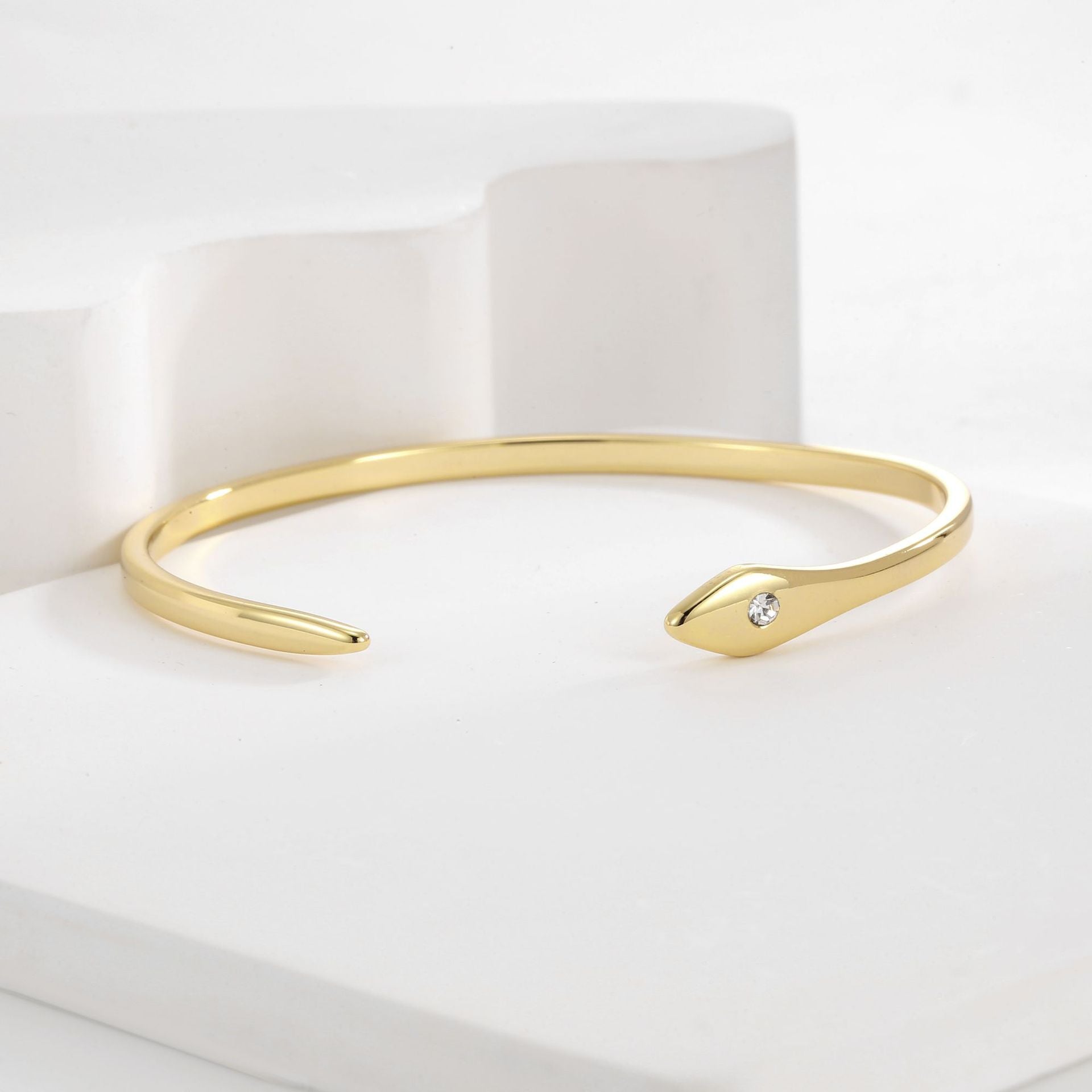 angled view of asymmetric gold plated cuff with pointed terminal