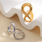 gold and silver sculptural infinity rings displayed by a white form