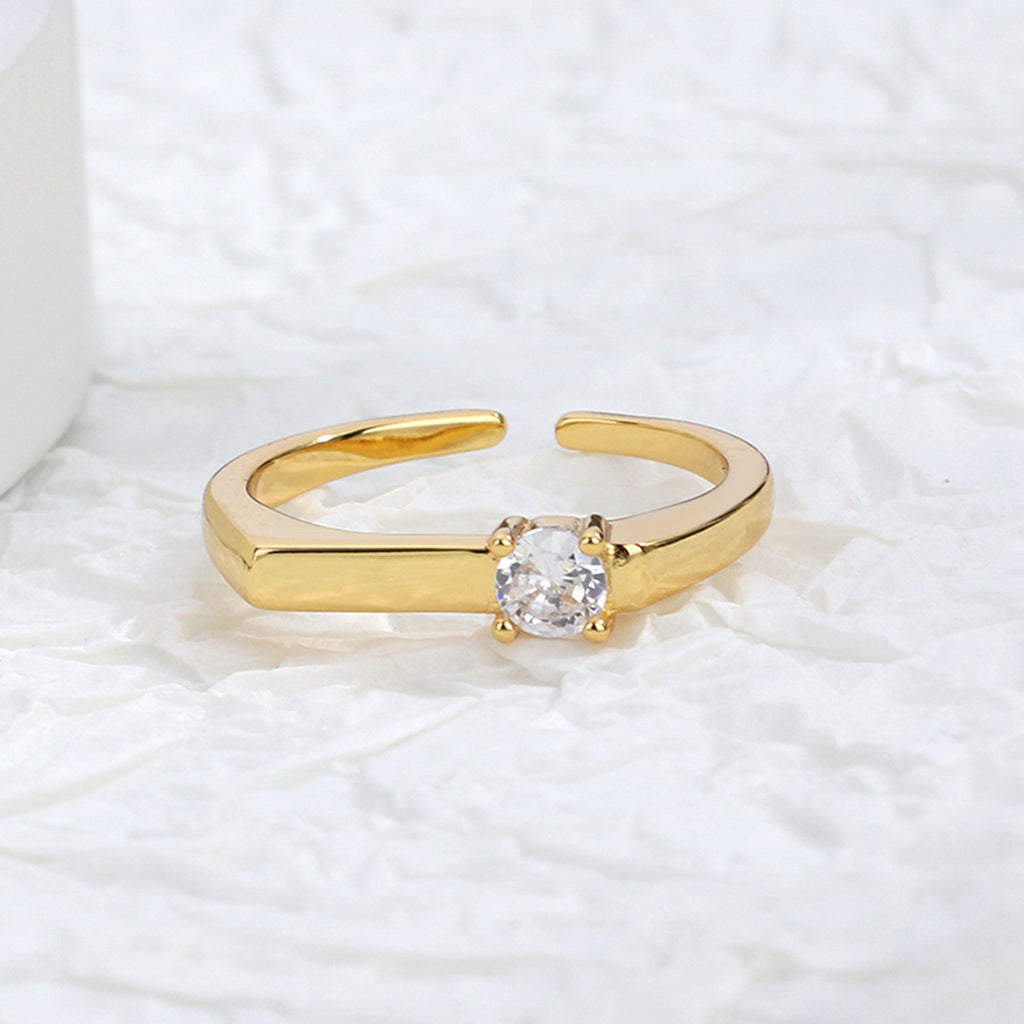 slim gold plated open ring displayed on a textured surface