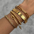 Five gold-tone chain bracelets and cuffs worn together