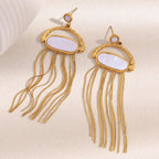 gold plated shell tassel drop earrings arranged on cream fabric
