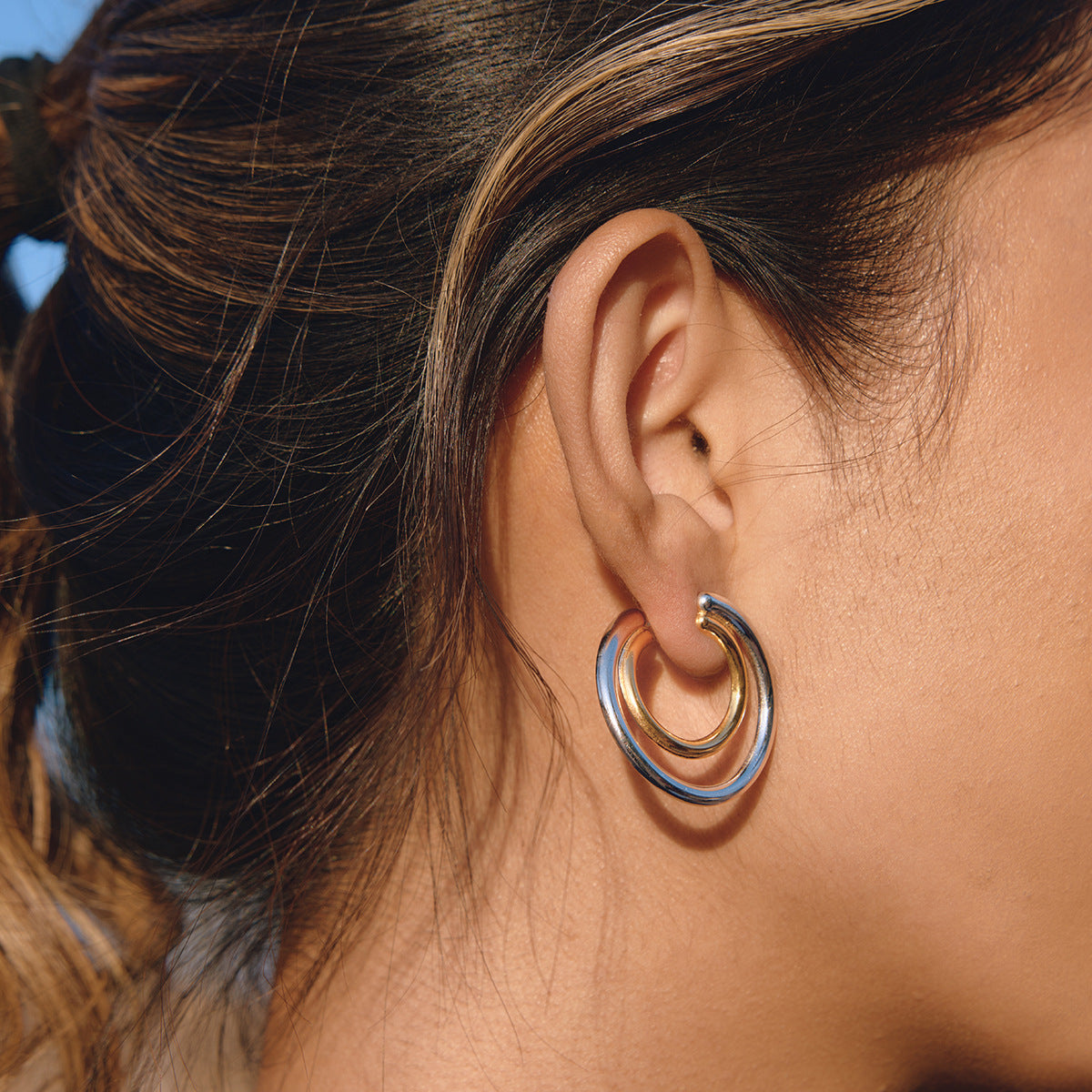 Angled wearing view of the gold inner hoop and silver-colored outer hoop