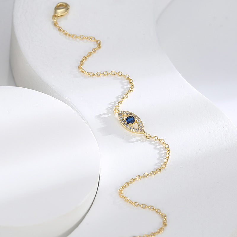 gold plated evil eye bracelet arranged diagonally on white display
