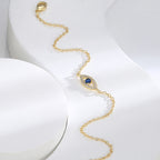 gold plated evil eye bracelet arranged diagonally on white display