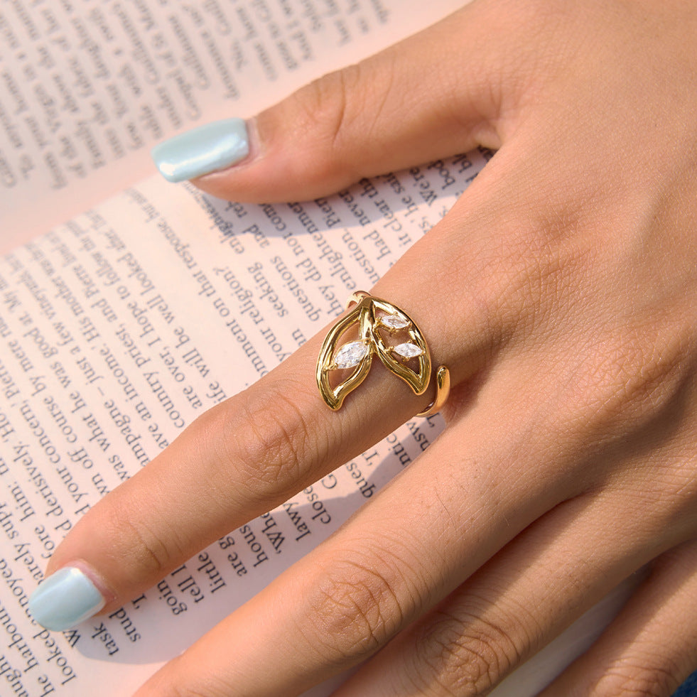 Gold tone botanical ring worn over an open book