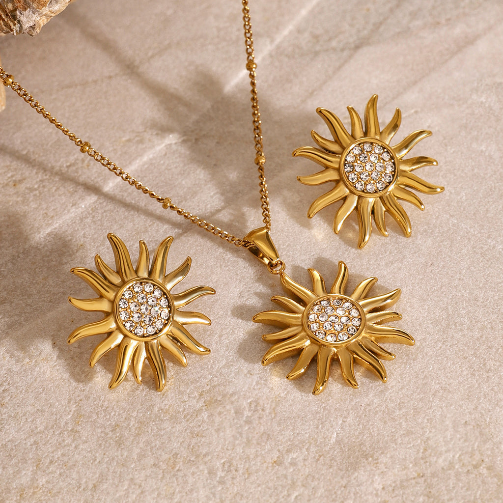 Sunburst pendant necklace and reference earrings displayed on stone