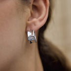 Silver-tone rectangular zirconia hoop worn on an ear