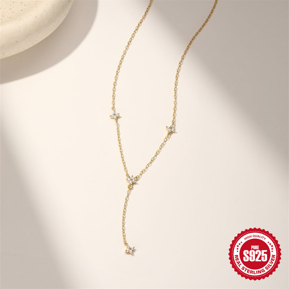 gold plated floral Y necklace arranged on a warm surface