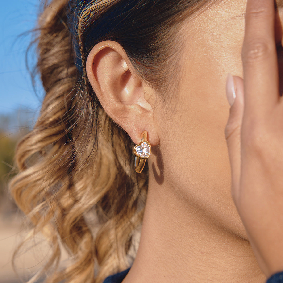 Gold-tone stainless steel heart hoop earrings worn on a model