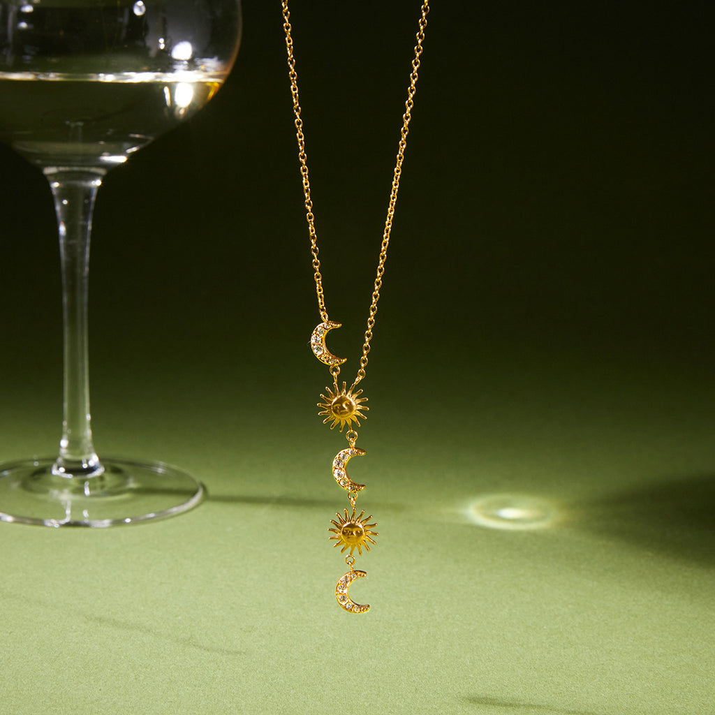 Gold-finish celestial Y necklace hanging against a green background