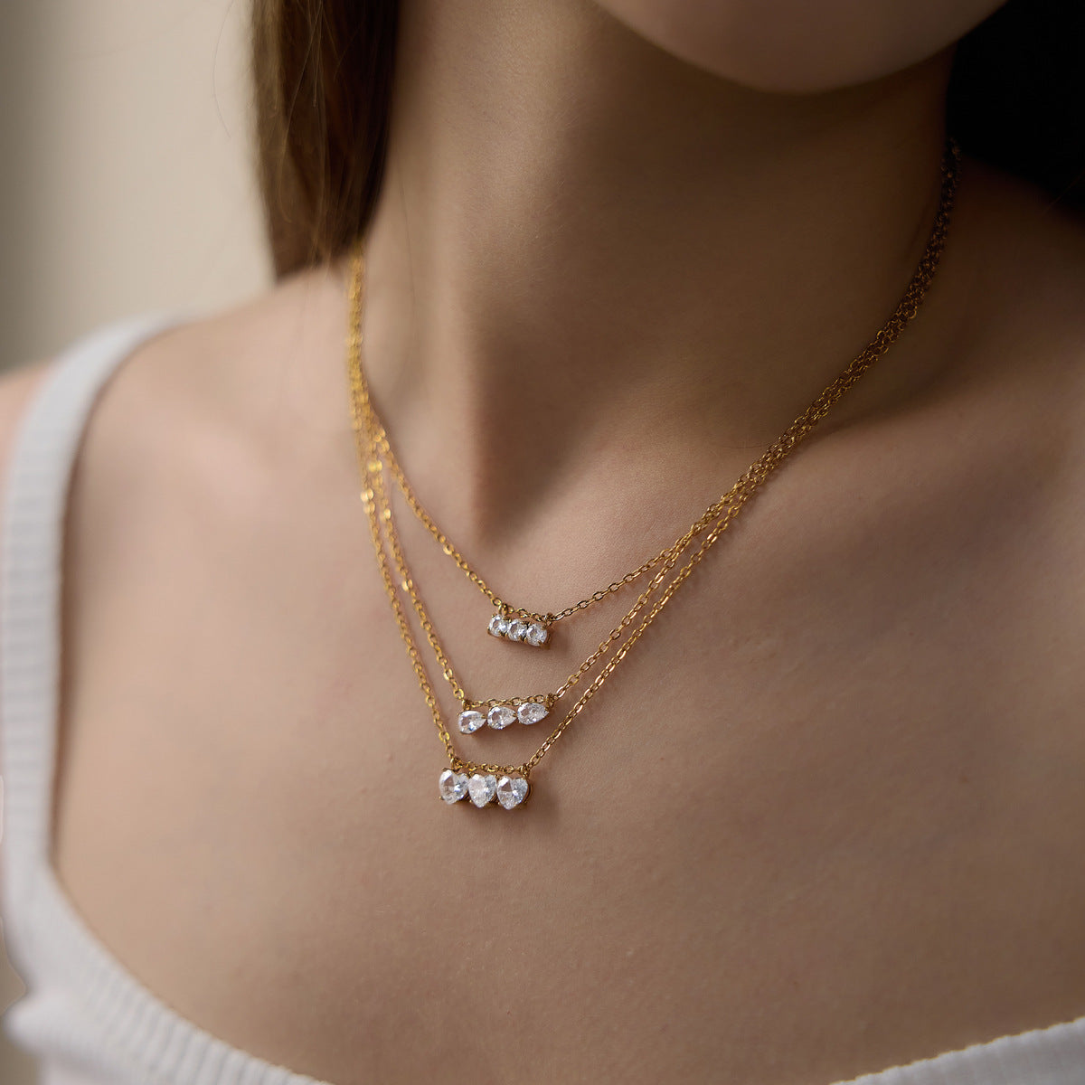 Side view of three separate triple-stone necklaces when worn