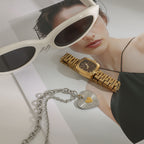 Two-tone heart pendant necklace arranged beside fashion accessories