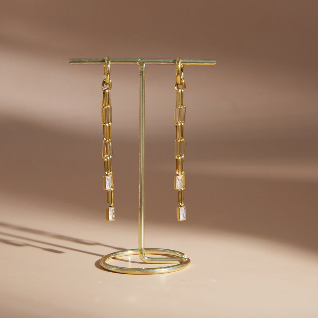 Pair of long chain drop earrings on a display stand