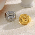 two stainless steel sculptural signet rings on a stone surface