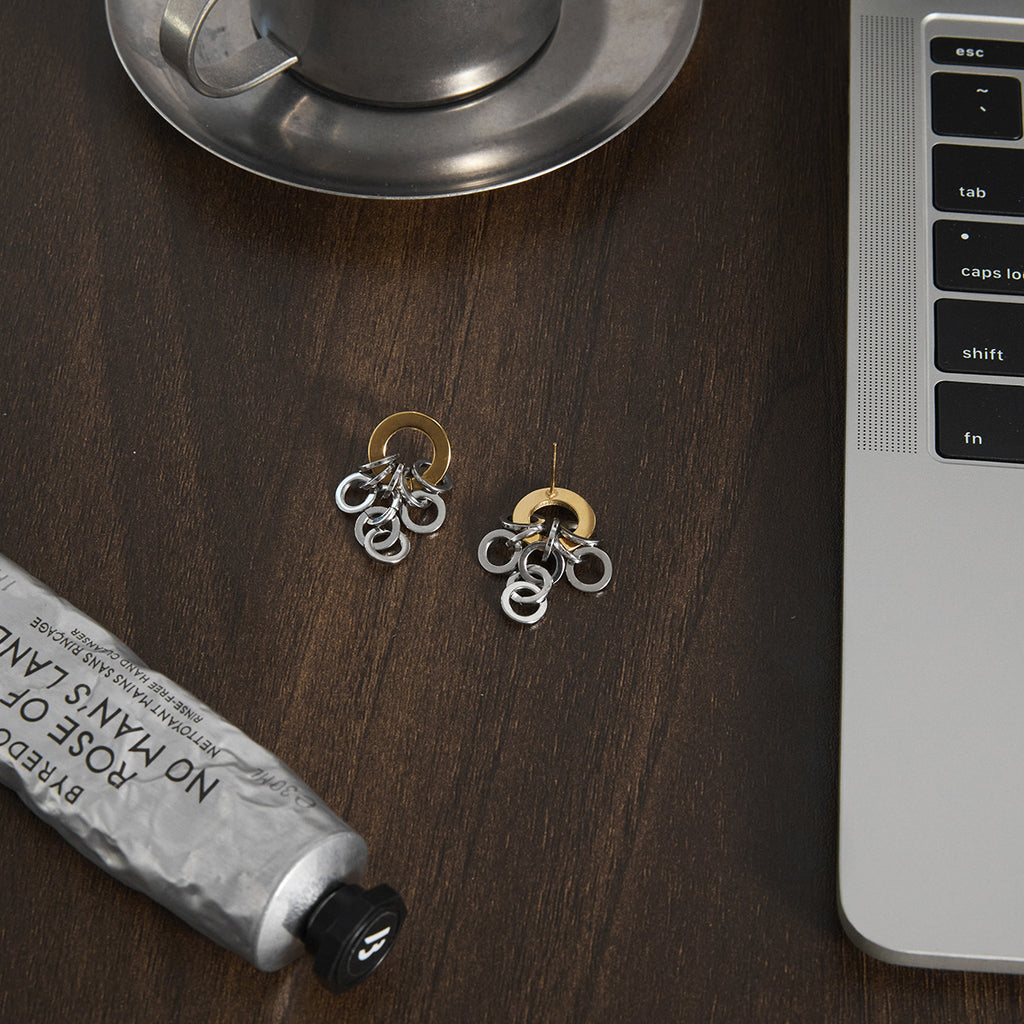 pair of two-tone stainless steel ring-cluster earrings on a desk
