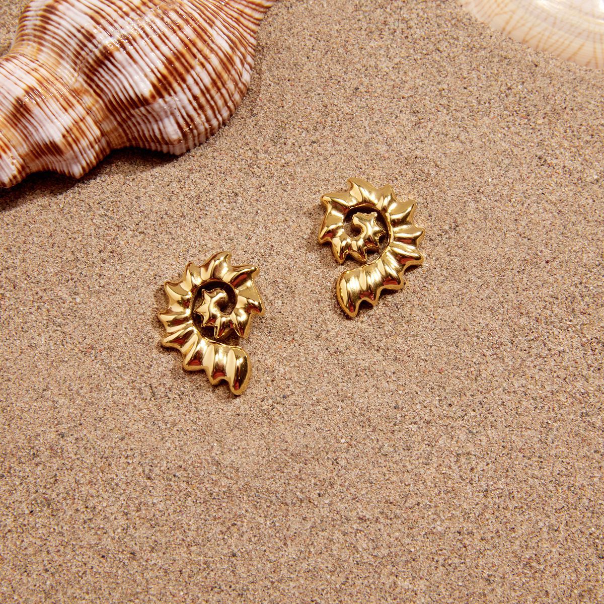 Open-spiral shell studs beside a seashell