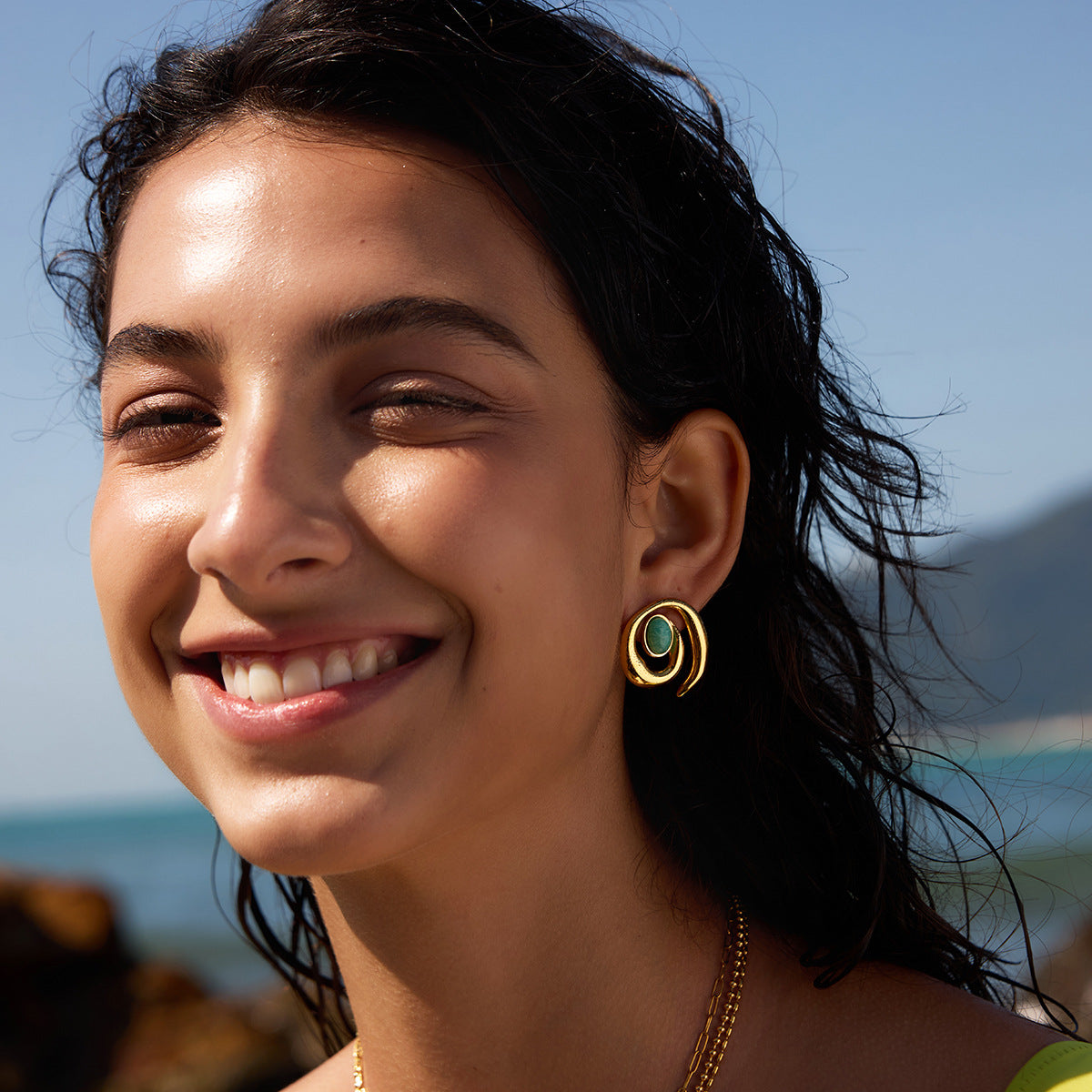 Green oval accent spiral earrings shown on a model