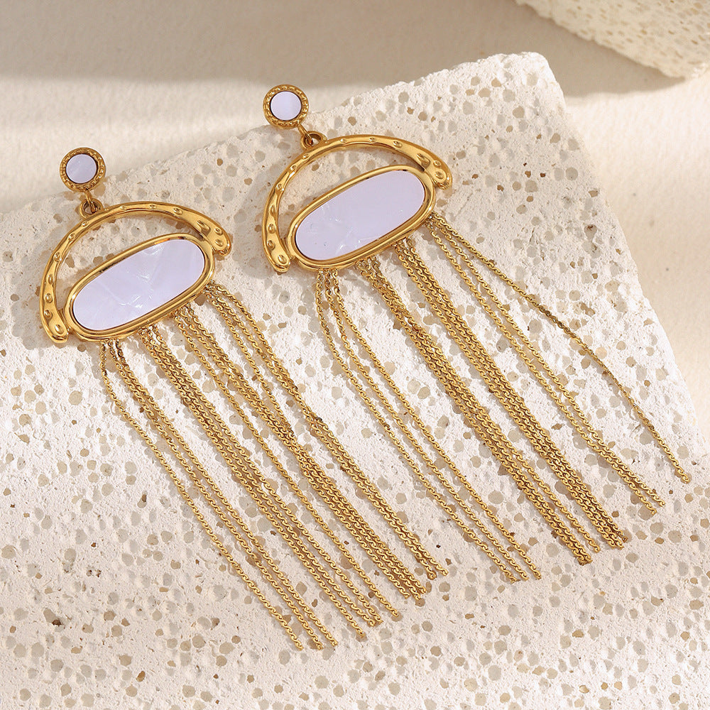 pair of pale shell chain fringe earrings styled on white stone