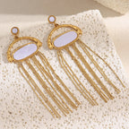 pair of pale shell chain fringe earrings styled on white stone