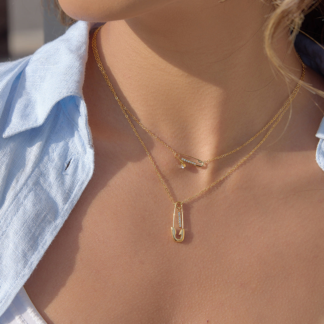 gold plated layered safety pin necklace worn at the collarbone