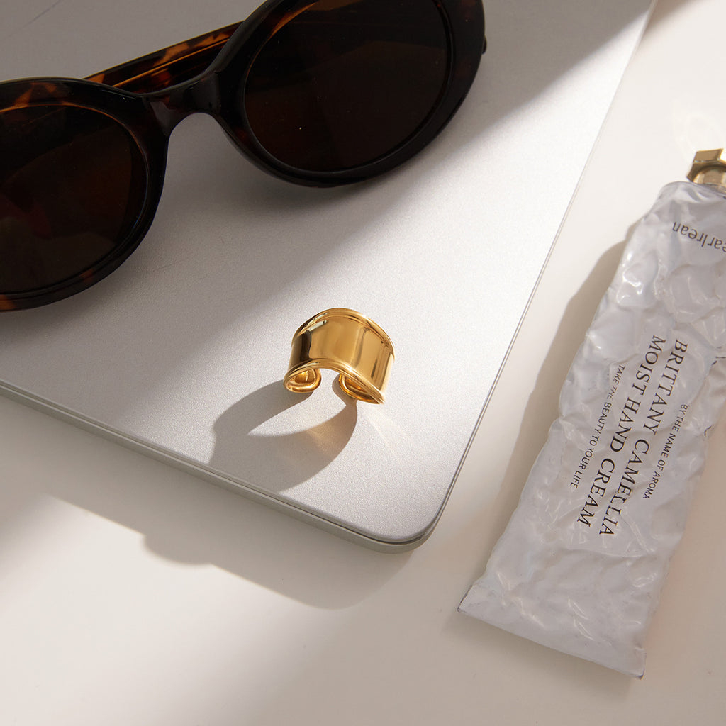 sculpted gold plated open ring on a neutral book